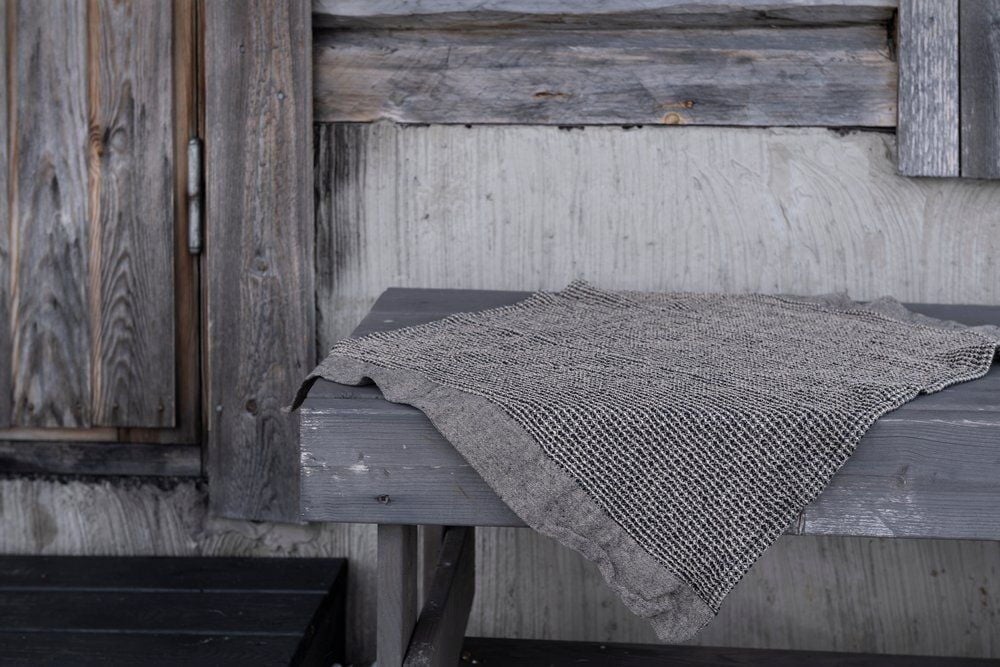 Musta-beige saunalautaliina puupenkillä.