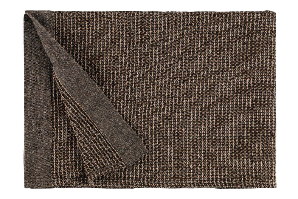 Musta ja beige saunapeitto reunalla.