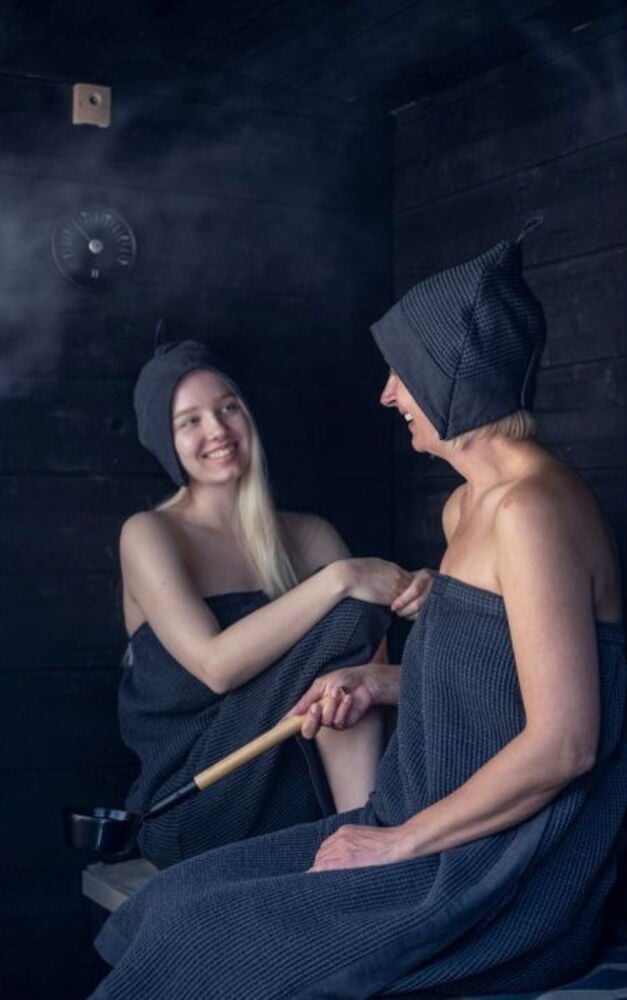 Kaksi henkilöä saunahatuissa saunassa.