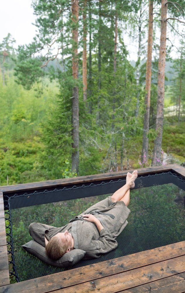 Henkilö makaa saunatyynyllä ulkona mustalla verkolla.