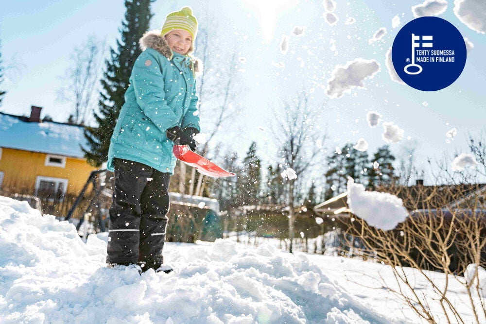 Lapsi punaisella lumilapiolla lumipeitteisellä maalla.