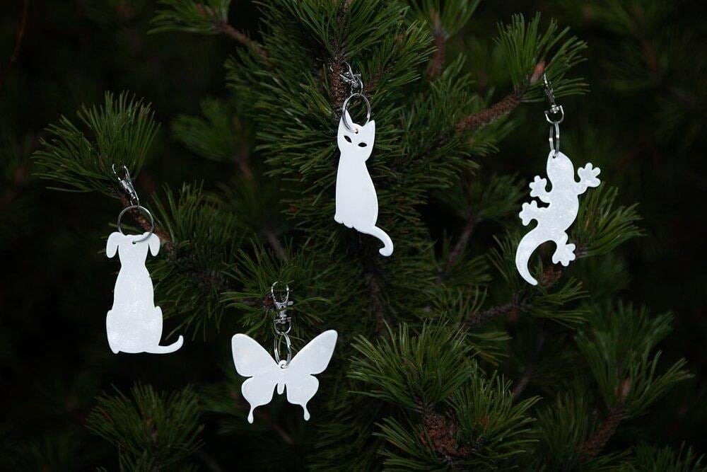 Neljä eläimenmuotoista heijastinta roikkuu vihreässä kuusessa.