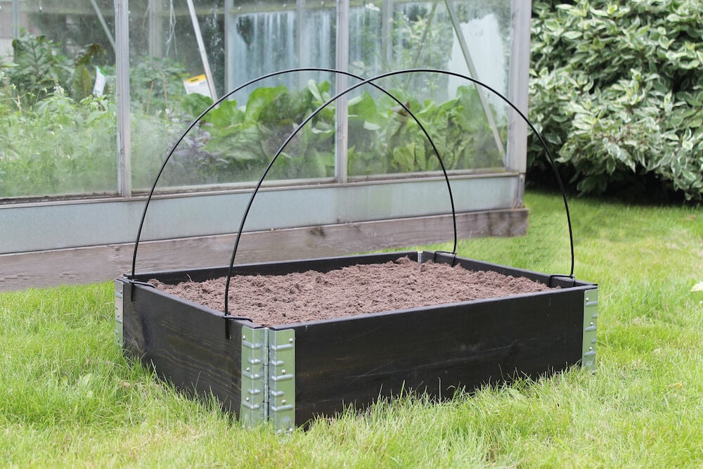 Kaksi mustaa tukikaarta ulkokäyttöön tarkoitetussa korotetussa viljelylaatikossa.