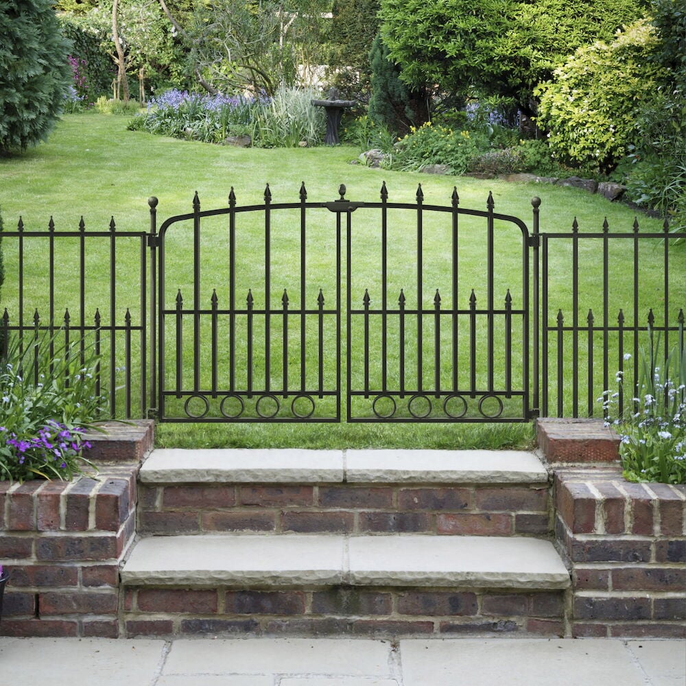 Musta metalliaita kivimuurin ja nurmikon välissä.