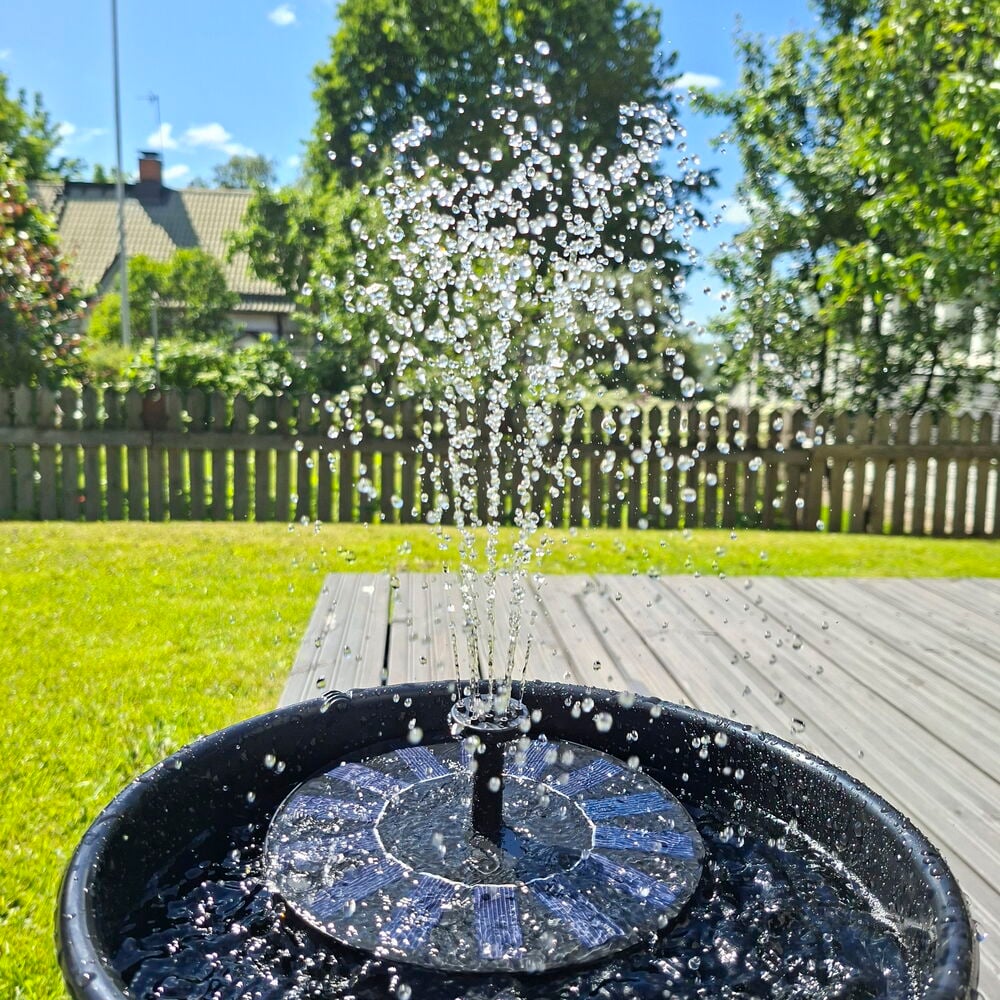 Suihkulähde aurinkokennolla Tarmo, musta pyöreä aurinkopaneeli, suihkuttaa vettä ruukussa.