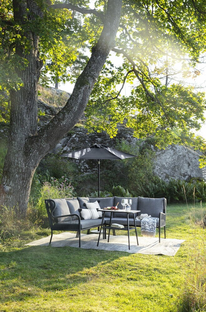 Musta lounge-setti pöydällä ja vettähylkivillä tyynyillä.