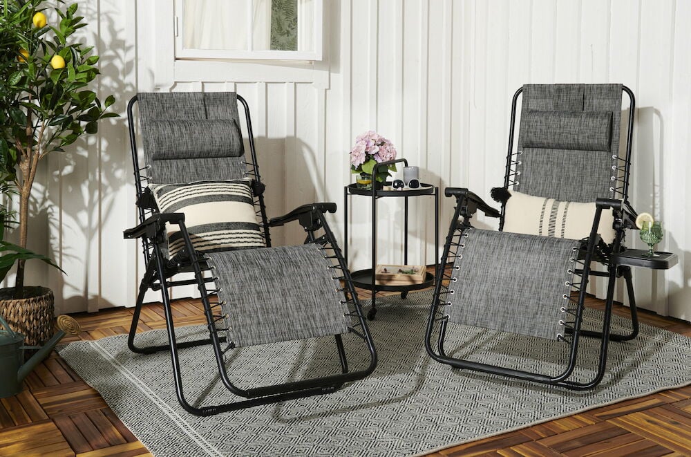 Två grå solstolar på altan med växter.