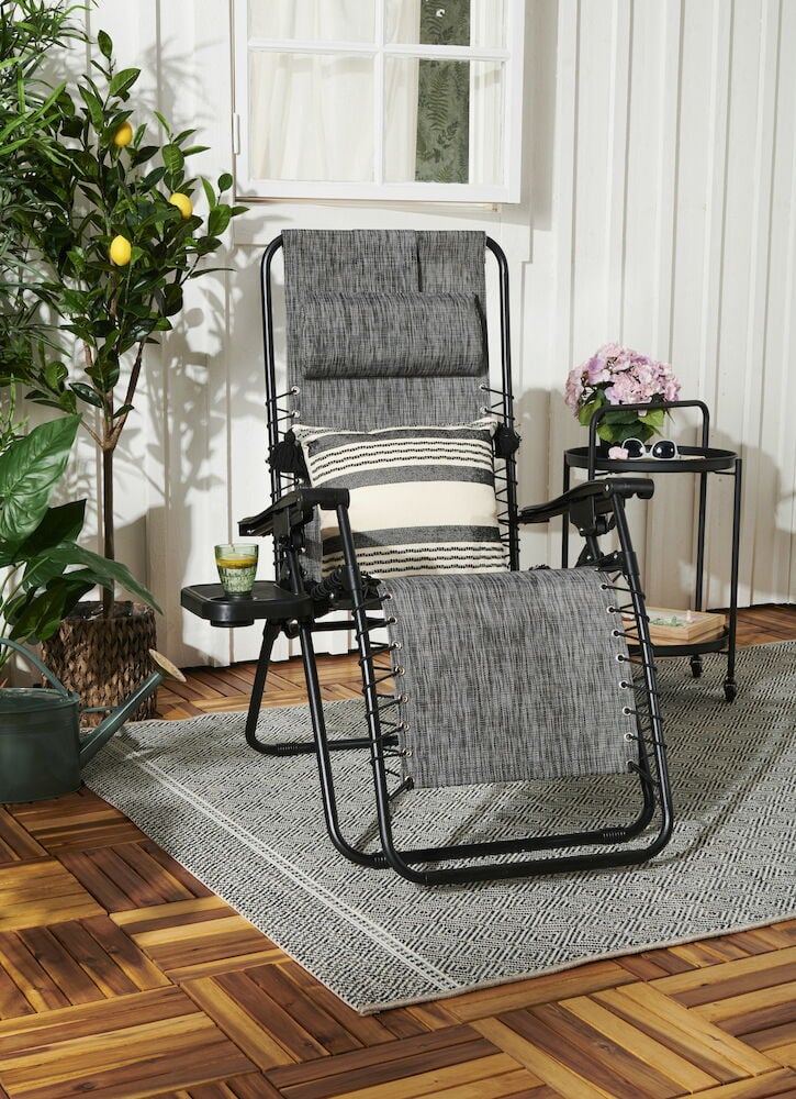 Gråmelerad solstol på altan med kuddar.