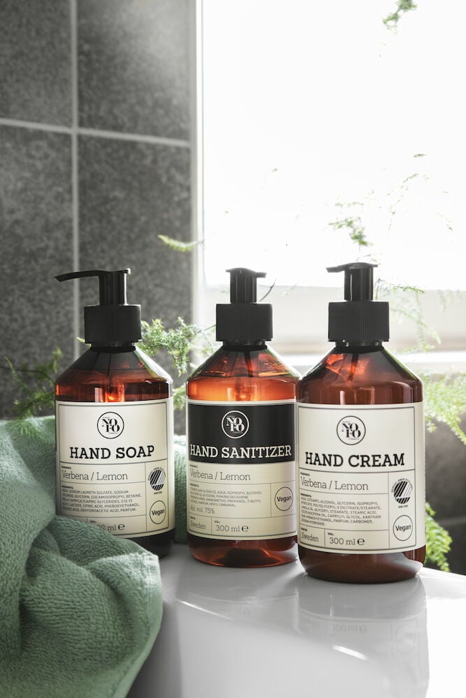 Tre bruna plastflaskor med etikett på badrumshylla.