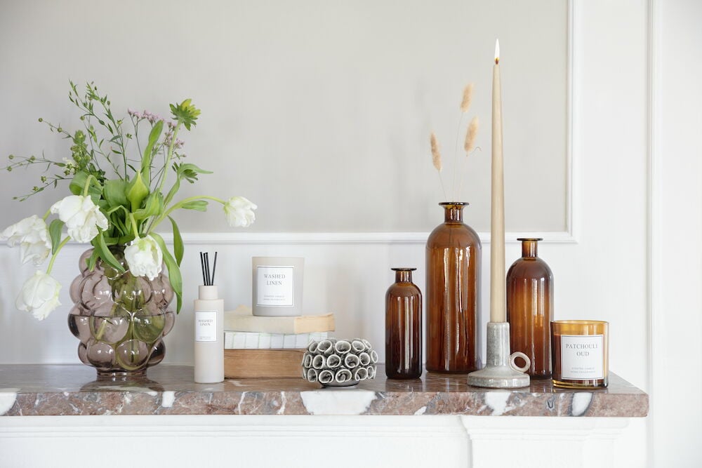 Beige tuoksukynttilä lasipurkissa marmorilevyllä.