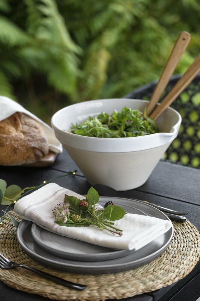 Beige puuvillainen keittiöpyyhe ulkona olevan lautasen päällä.