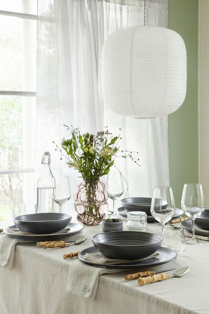 Valkoinen riisilyhty roikkuu katetun ruokapöydän yläpuolella.