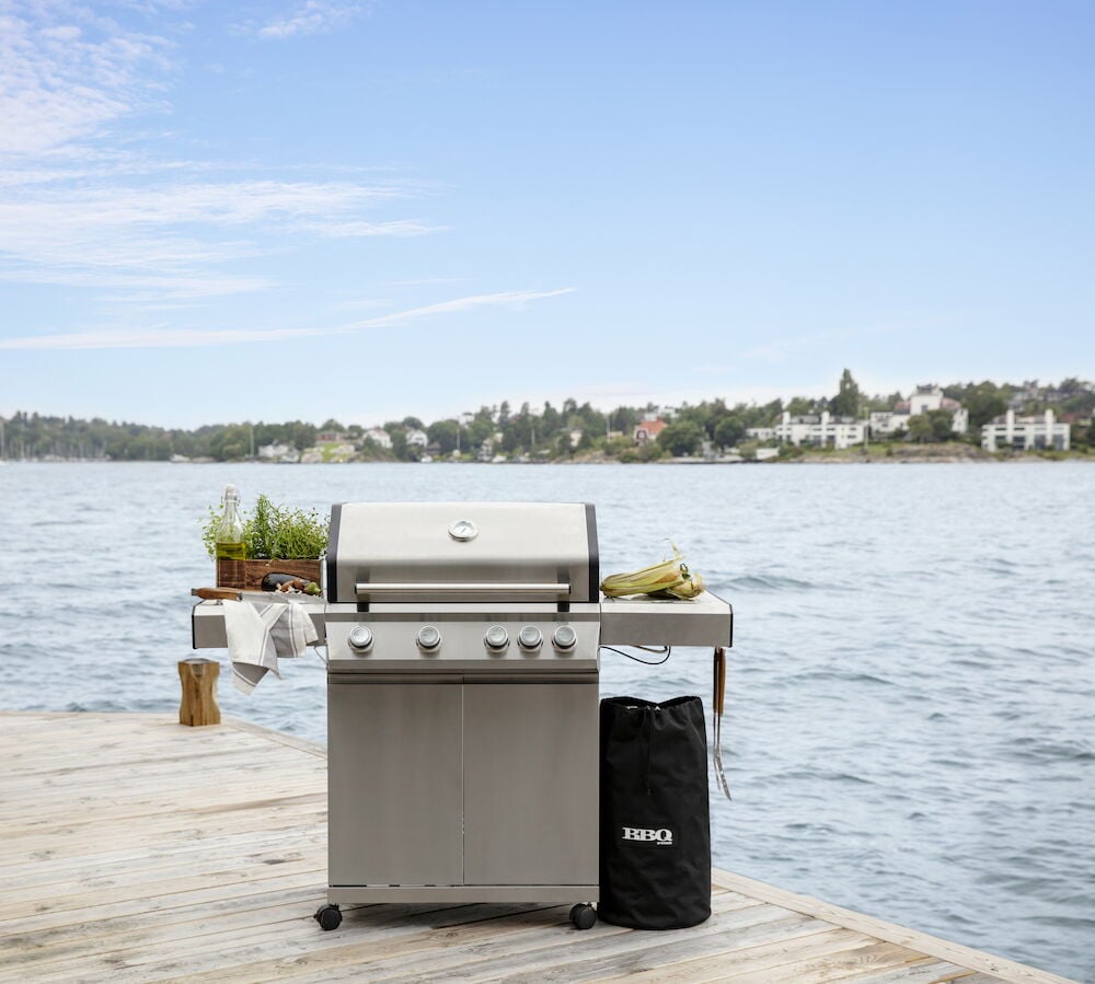 Svart gasolflasköverdrag bredvid grill på brygga.