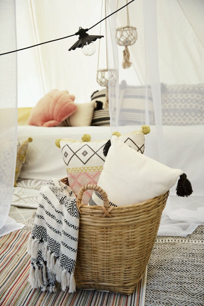 Geflochtener Bambuskorb mit Griff, gefüllt mit Kissen.