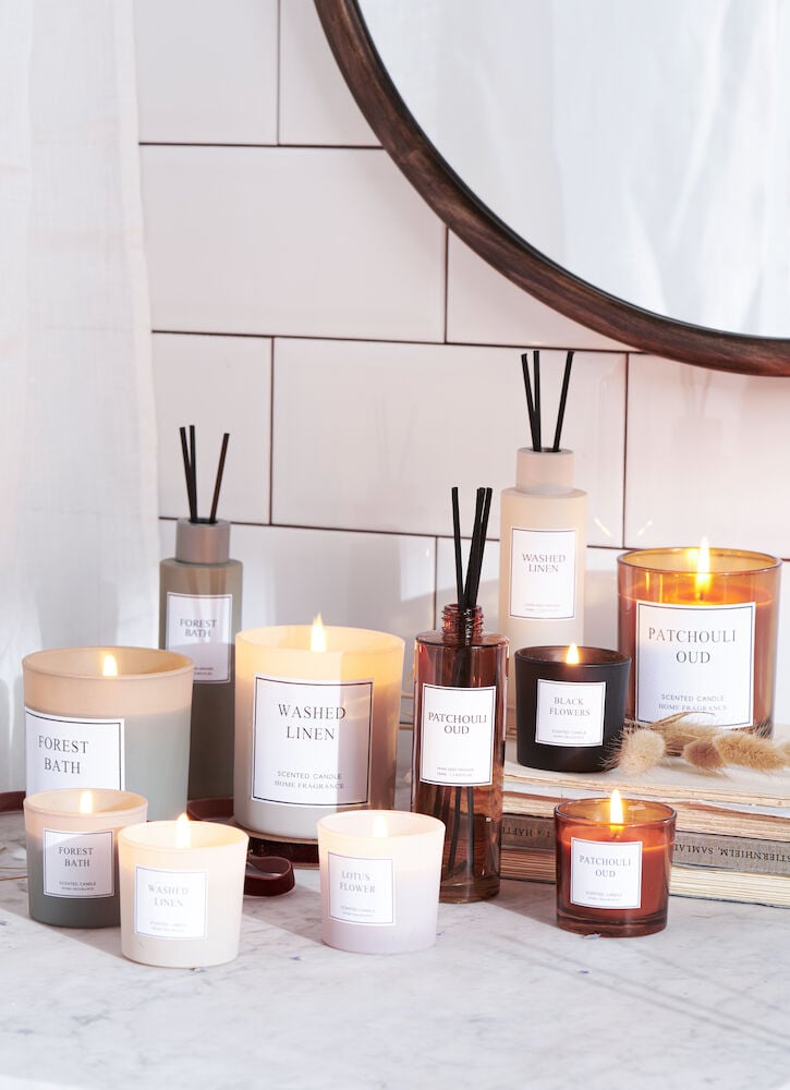 Flera doftljus i glasbehållare på marmorbord.