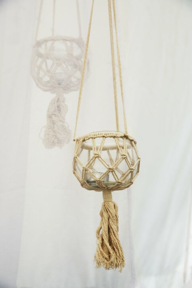 Lasinen roikkuva lyhty, jossa on makrameepäällinen.
