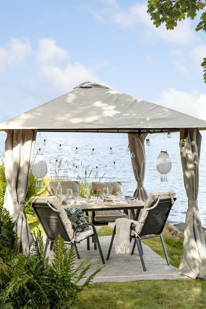 Hvitt spisebord med seks stoler under paviljong.