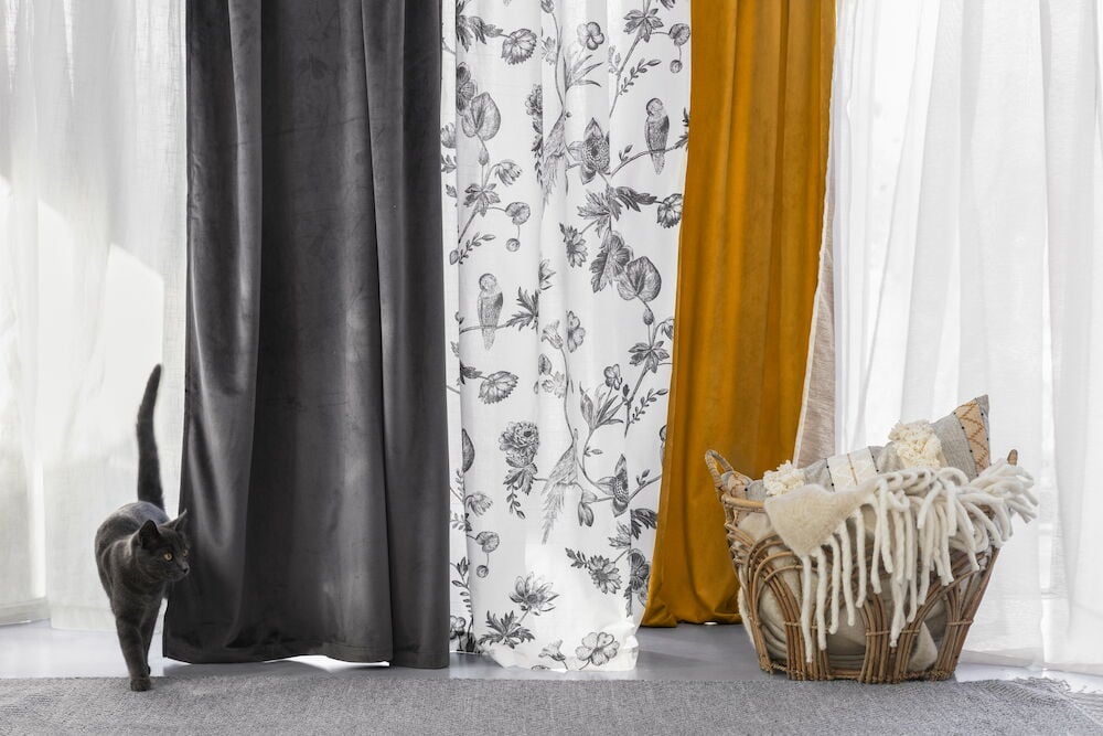 Kaksi valkoista puuvillaverhoa roikkuu muiden verhojen vieressä.