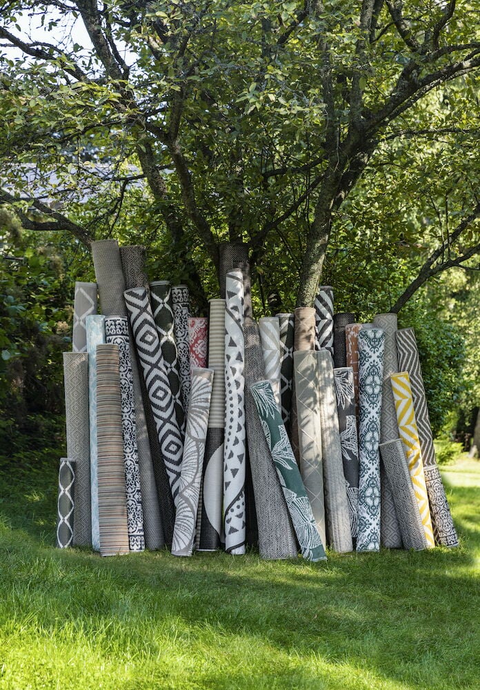 Utrullade mattor i olika mönster under ett träd.