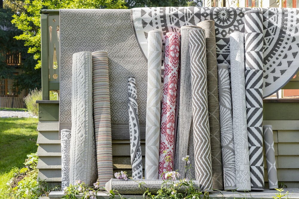 Flera upprullade utomhusmattor i olika mönster och färger.