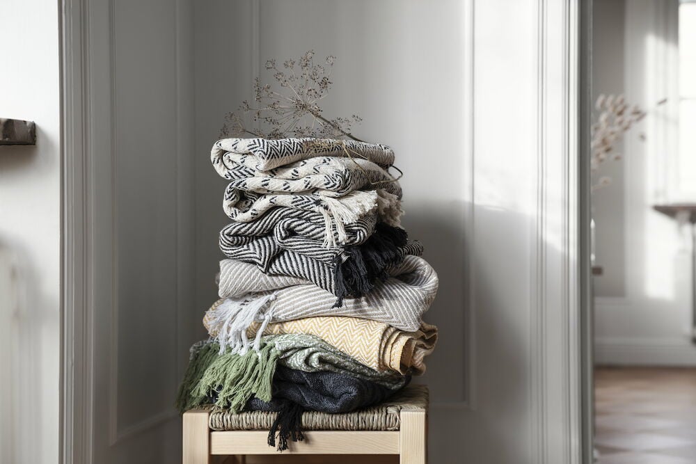 Flera vikta filtar i olika mönster och färger.