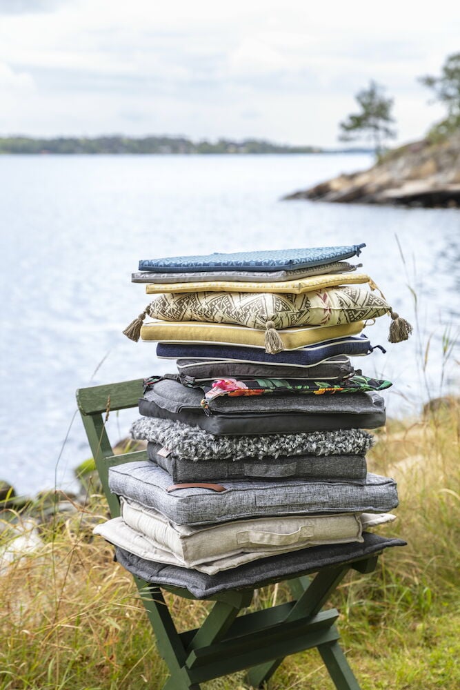 Pino tuolityynyjä ulkona veden äärellä.