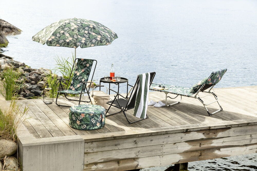 Handtuch Baden 170x58 cm Bea Paradise, gestreift, auf schwarzem Stuhl, mit gemustertem Schirm und Möbeln am Steg.