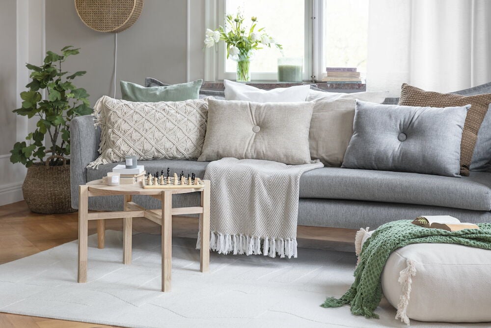 Tuoksukynttilä lasisäiliössä olohuoneen sohvapöydällä.