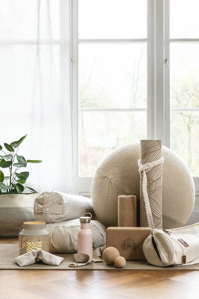 Yogakudde och tillbehör i ljust rum med fönster.