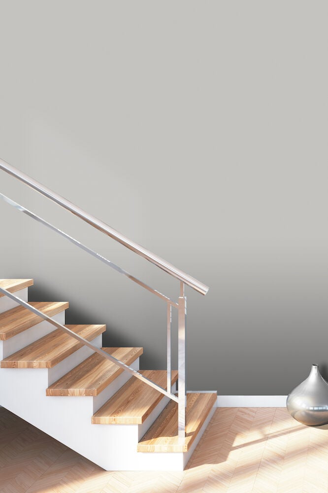 Mörkgrå slät tapet bakom trätrappa och vas.