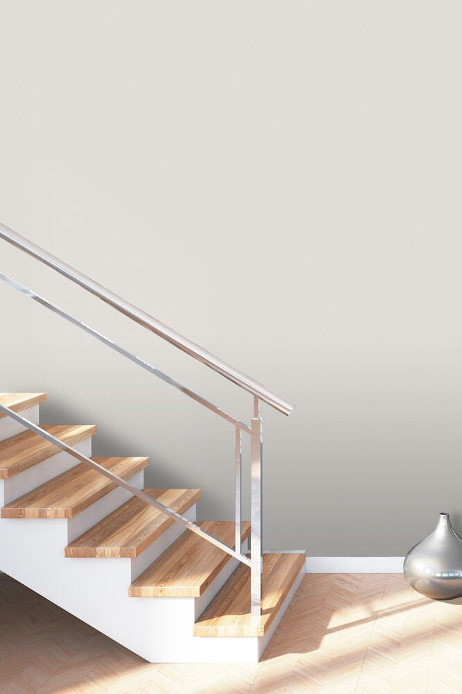 Ljusgrå slät tapet bakom trappa och dekorvas.