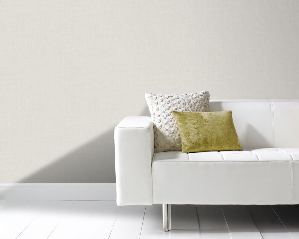 Ljusgrå skimrande tapet bakom vit soffa.