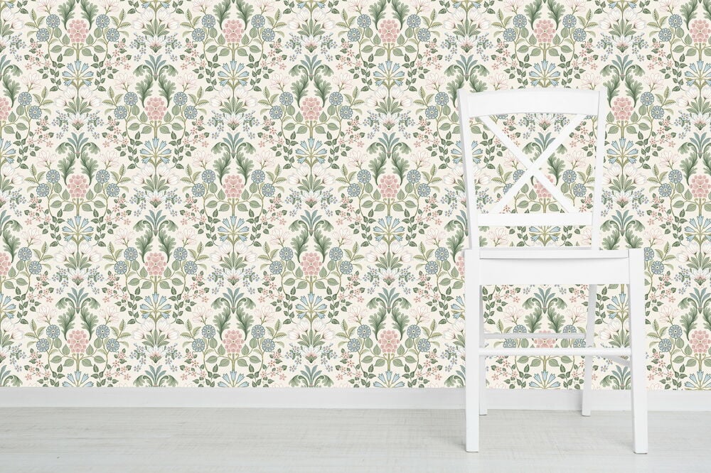 Vit stol framför mönstrad medaljongtapet i pastellfärger.