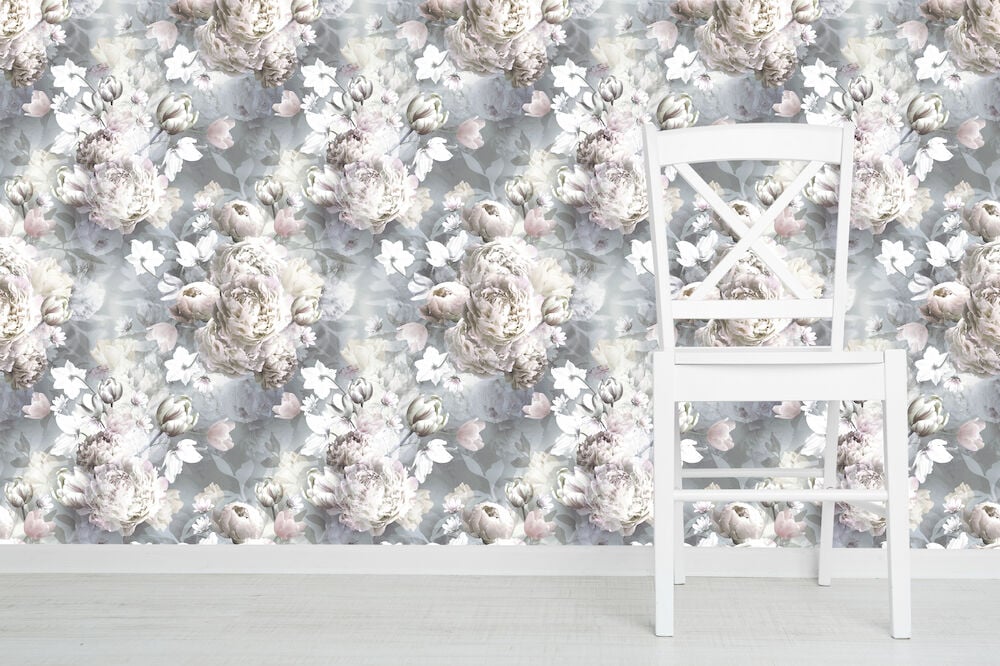 En vit stol framför blommig pastellfärgad tapet.