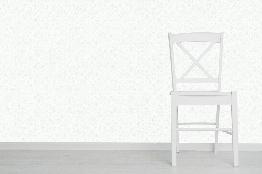 Vit stol framför grå tapet med nyponrosmönster.