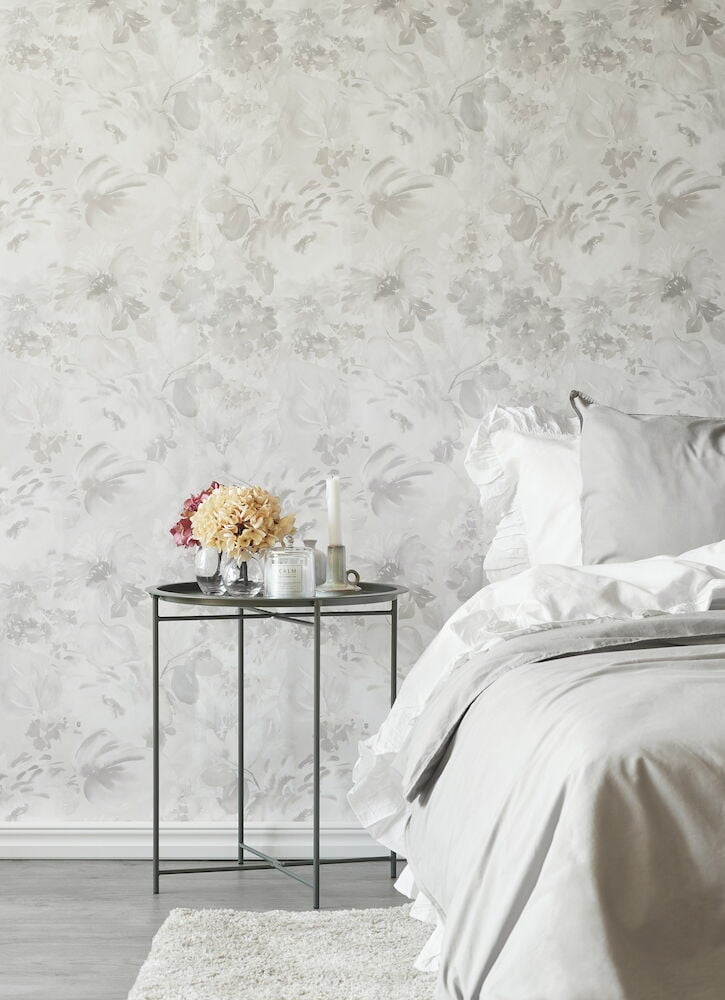 Blommig grå rosa tapet och bäddad säng i sovrum.