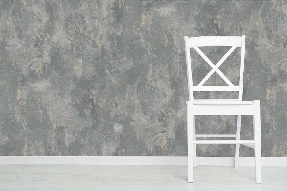 Vit stol framför blå texturtapet i rum.