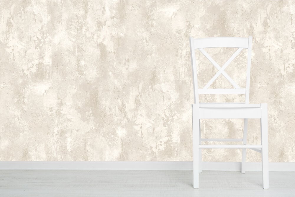 Valkoinen tuoli kermanvärisen tekstuuritapetin edessä.