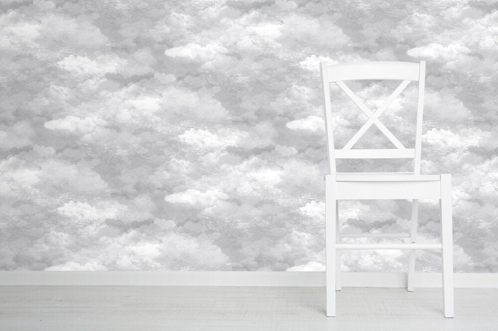 Vit stol framför grå molnmönstrad tapet.