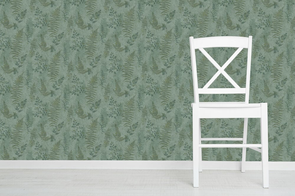 Vit stol framför grön mönstrad ormbunketapet.