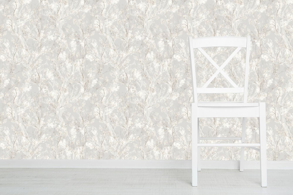 Vit stol framför grå bomullsblommig tapet.