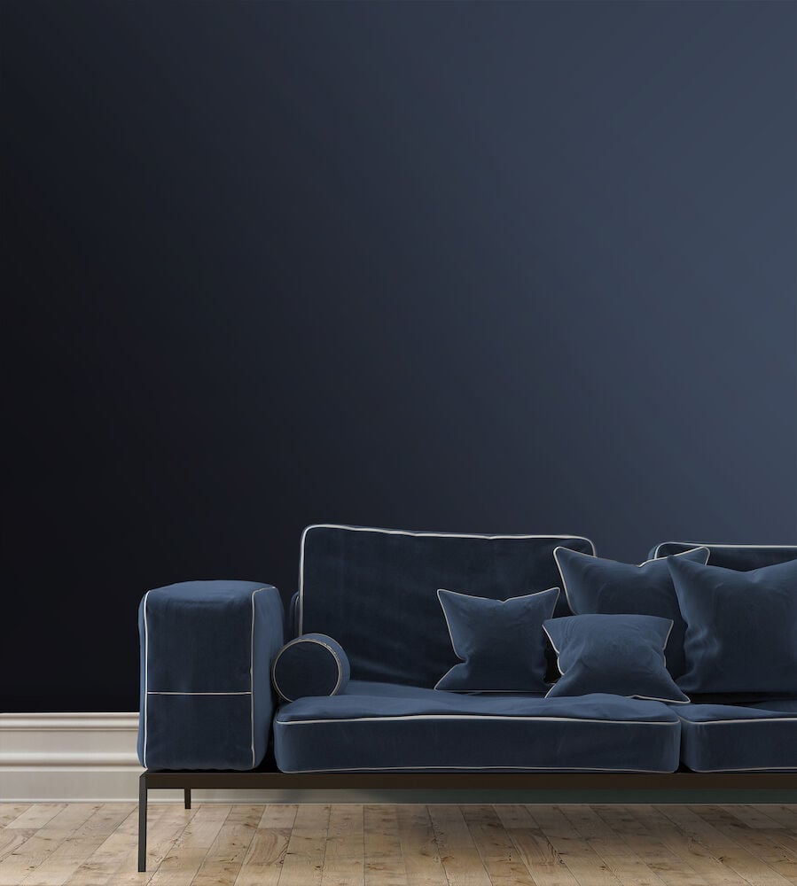 Blå matt tapet bakom soffa med kuddar.
