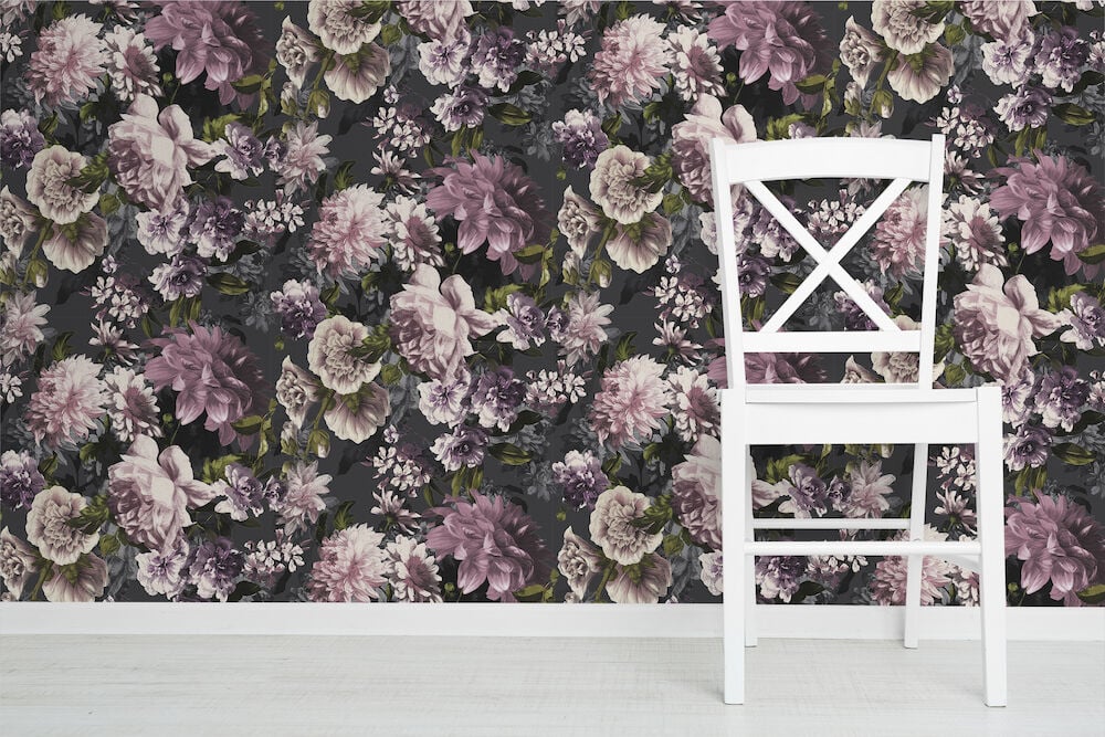 Vit stol framför blommig tapet i svart och rosa.