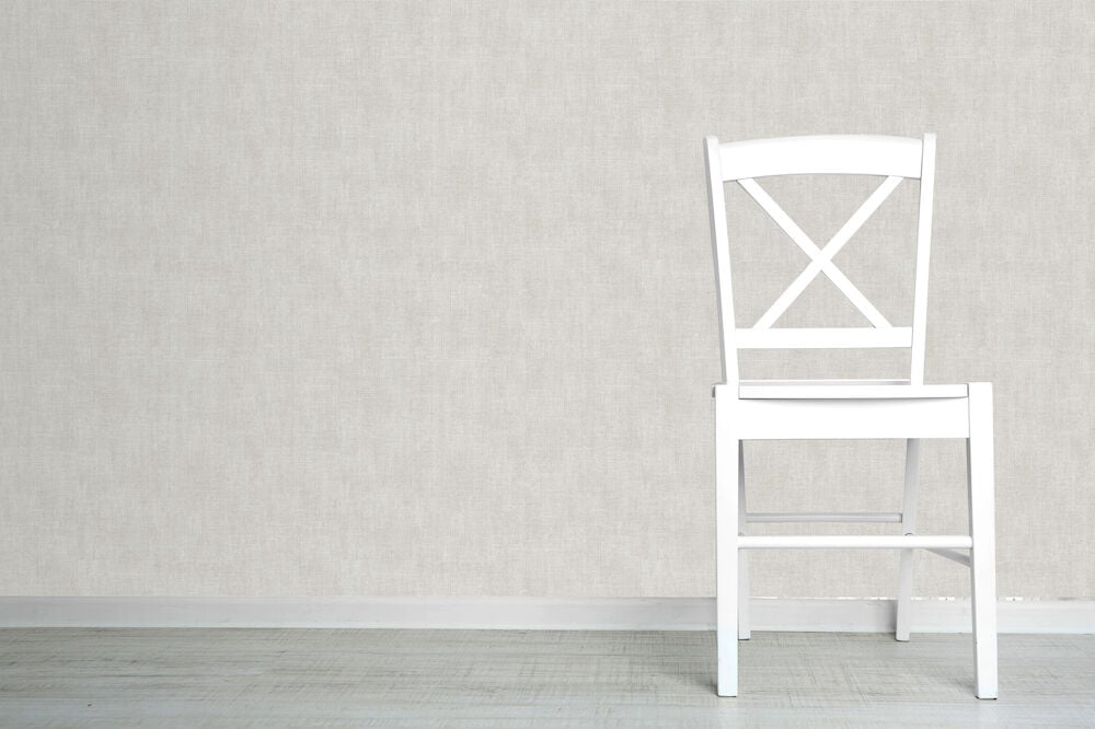 Vit stol framför gråbeige texturtapet och ljust golv.