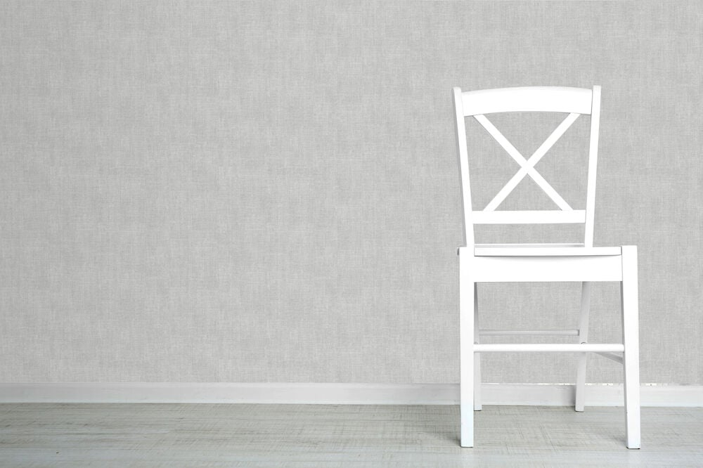 Vit stol framför mörkgrå texturerad tapet.