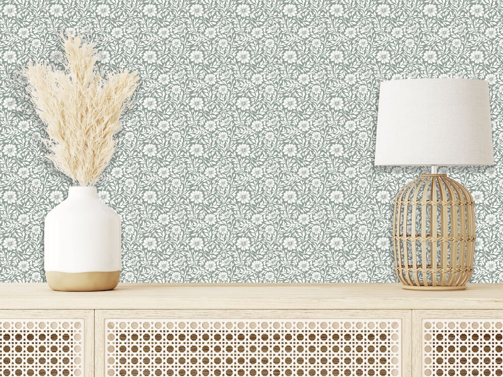 Grön tapet med mönster bakom lampa och vas.