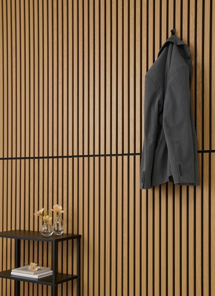 Ljus akustikpanel med svarta linjer och upphängd kavaj.