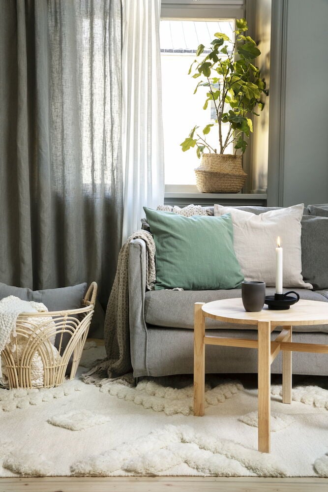 Vit kuddfodral på grå soffa i vardagsrum.