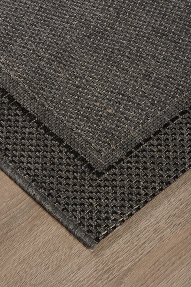 Grå matta med dekorativ kant på trägolv.