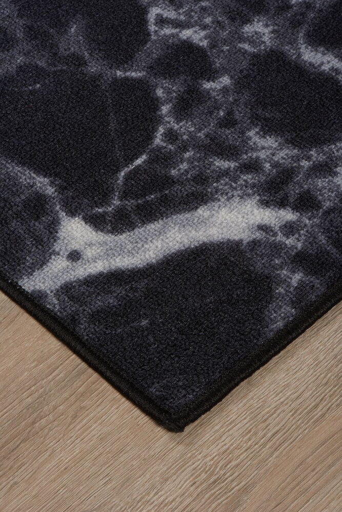 Kulma mustavalkoista modernia mattoa puulattialla.